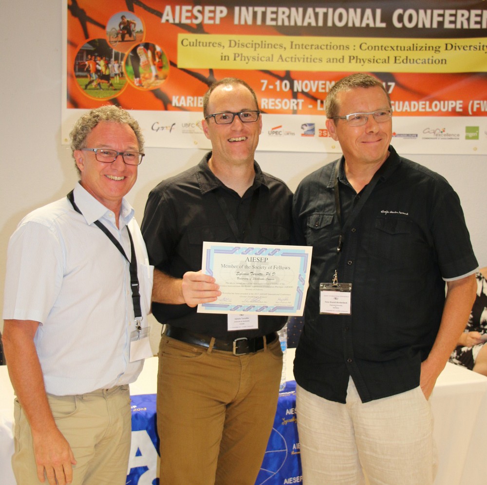 Le professeur Sylvain Turcotte a re&ccedil;u le titre de Fellow de l&rsquo;AIESEP. On le voit en compagnie du professeur Marc Cloes, pr&eacute;sident de l&rsquo;AIESEP, et du professeur Hans Peter Brandl-Bredenbeck, responsable du Fellowship Award.