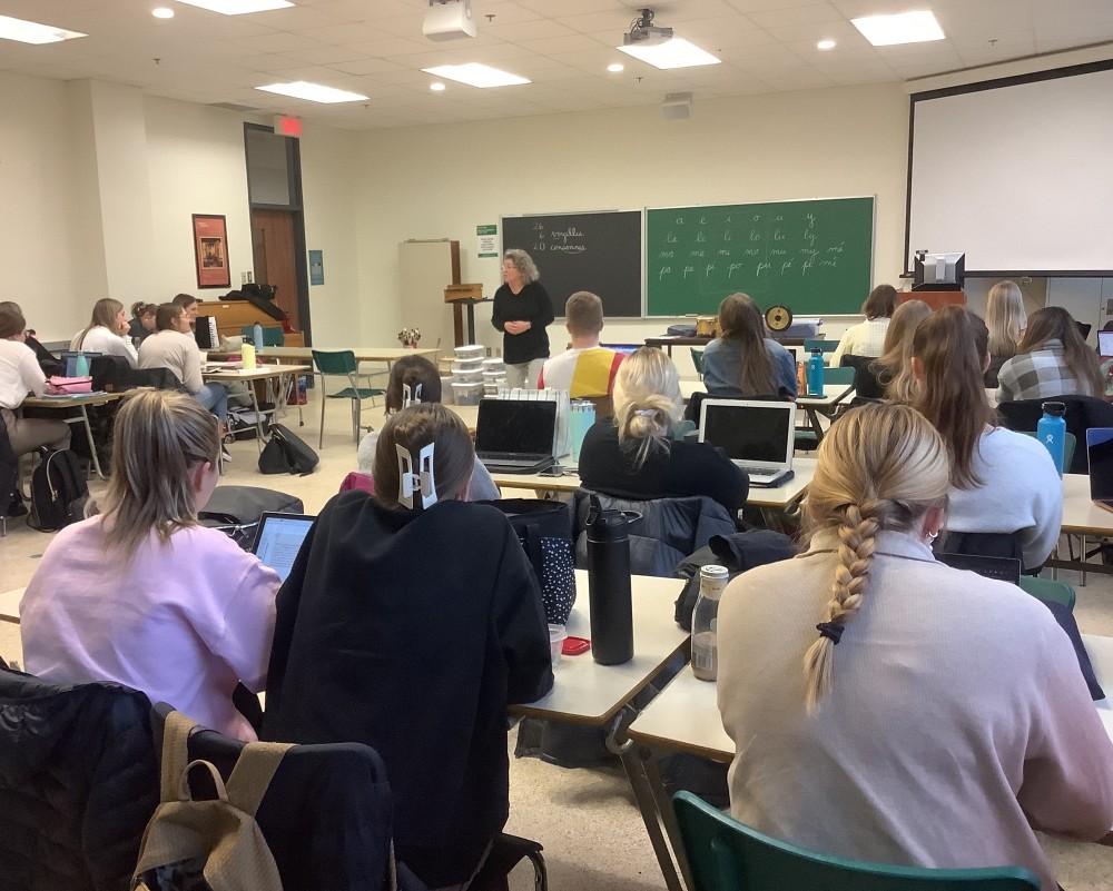 Maryl&egrave;ne Gilbert, enseignante retrait&eacute;e de 1re ann&eacute;e de l'&eacute;cole du Sacr&eacute;-Coeur devant un groupe de personnes &eacute;tudiantes du cours Initiation &agrave; la musique.