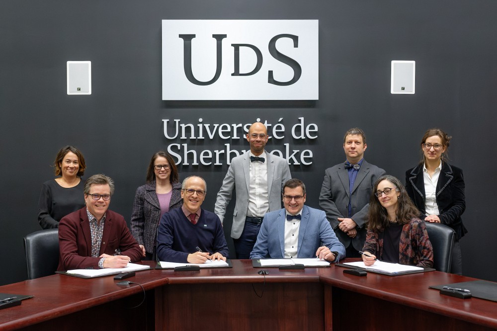 Les signataires du nouveau contrat de travail, Pr&nbsp;Patrik Doucet, vice-recteur aux ressources humaines; Pr&nbsp;Pierre Cossette, recteur; Robin Renaud et Marie-France No&euml;l, respectivement pr&eacute;sident et vice-pr&eacute;sidente de l&rsquo;APAPUS.&nbsp;Debout&nbsp;: Carolyne Raymond et Julie Labelle, conseill&egrave;res en gestion des ressources humaines &agrave; l&rsquo;UdeS; Pascal Morin, conseiller de l&rsquo;APAPUS; Guillaume Arguin, conseiller de l&rsquo;APAPUS (recherche); Mathilde Valentini, conseill&egrave;re &agrave; la FPPU.