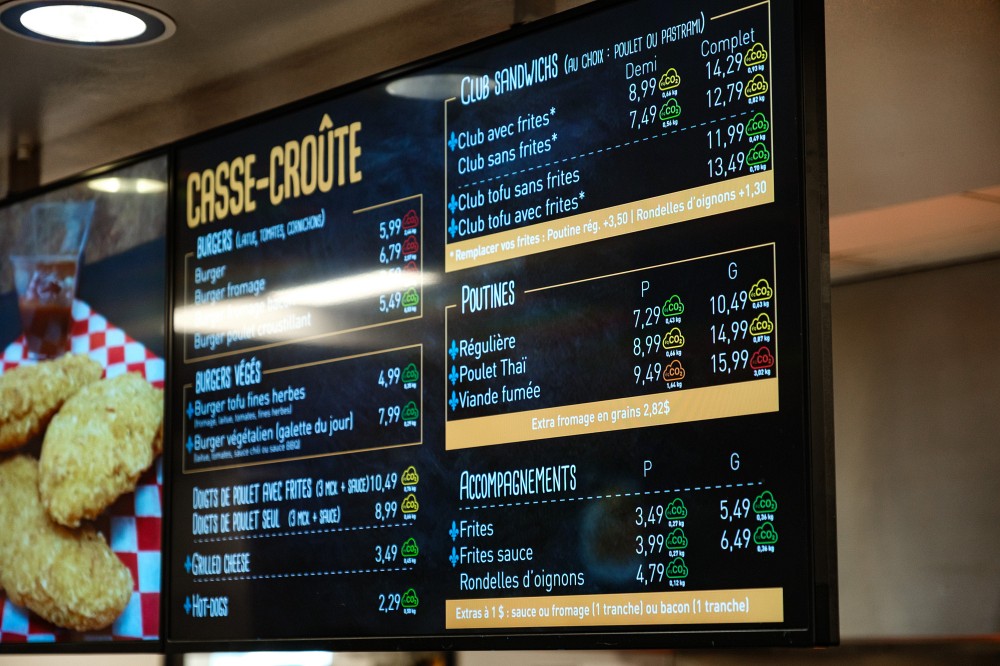 Le logo de nuage utilise un code de couleurs inspir&eacute; des feux de circulation, accompagn&eacute; de la quantit&eacute; d&rsquo;&eacute;quivalent CO₂ &eacute;mise pour chaque plat. Les repas consid&eacute;r&eacute;s locaux, identifi&eacute;s par la fleur de lys, sont ceux pour lesquels au moins 50 % du poids des ingr&eacute;dients sont de provenance qu&eacute;b&eacute;coise.