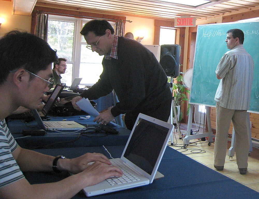 Sur la photo, apparaissent les professeurs Michel Côté de l'Université de Montréal (au tableau) et Xavier Gonze de l'Université Catholique de Louvain (au bureau) dirigeant une session de travaux pratiques sur le logiciel publique ABINIT