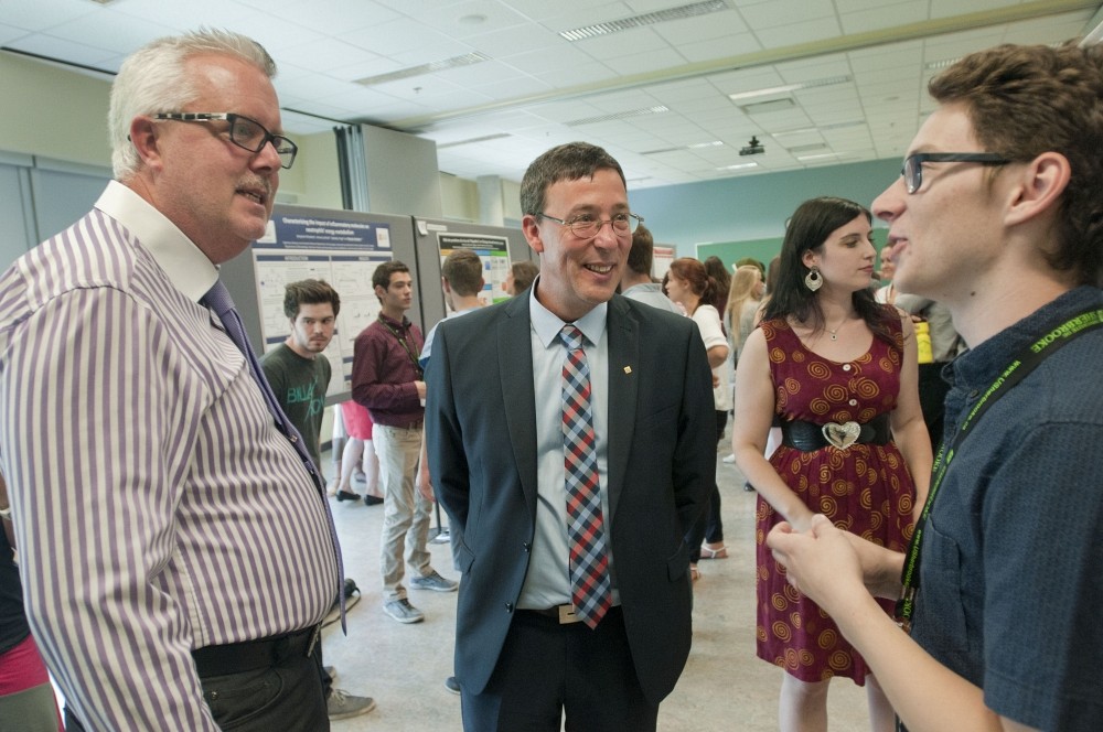 Monsieur Miles Turnbull, vice-principal acad&eacute;mique &agrave; l'Universit&eacute; Bishop's et le Pr Jean-Pierre Perreault, vice-doyen &agrave; la recherche et aux &eacute;tudes sup&eacute;rieures discutent avec Cameron Levins.