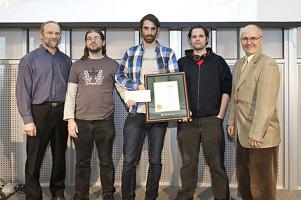 Alexei Nordell-Malkovits, Keven Marin et Alexandre L&eacute;tourneau, repr&eacute;sentants du groupe Hackus, re&ccedil;oivent le prix des mains de Martin Buteau, vice-recteur aux ressources humaines et &agrave; la vie &eacute;tudiante, et du professeur Gabriel Girard, directeur du D&eacute;partement d'informatique.