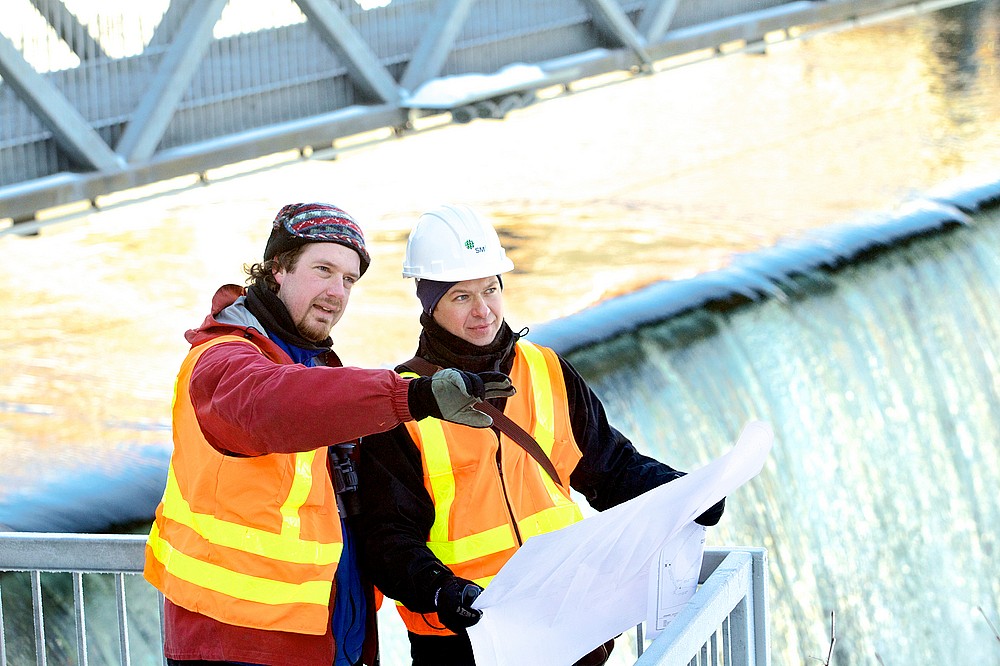 &Eacute;ric, &eacute;cologiste, et Anderson, ing&eacute;nieur, discutent de mesures d'att&eacute;nuation environnementales pour la r&eacute;fection d'un barrage.