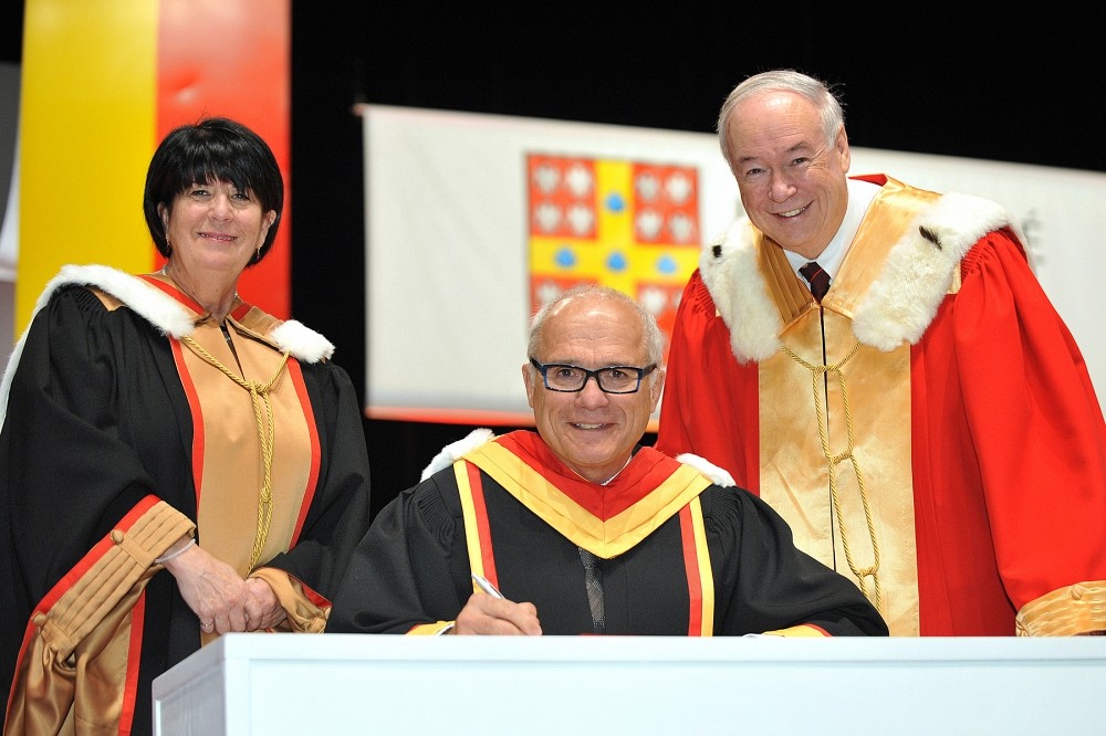 Le professeur Grand'Maison signe un registre, entour&eacute; de la secr&eacute;taire g&eacute;n&eacute;rale Monique Richer et du recteur Denis Bri&egrave;re de l'Universit&eacute; Laval.