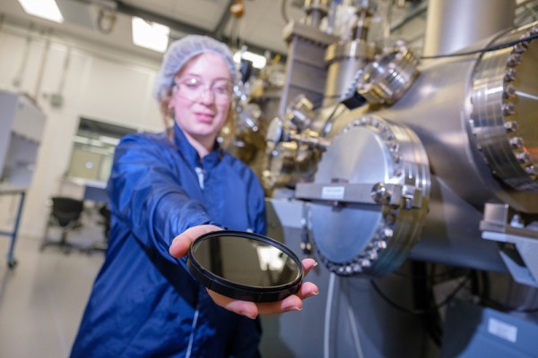 Laurie Mouchel, qui tient un substrat, aux c&ocirc;t&eacute;s d'&eacute;quipements d'&eacute;pitaxie.