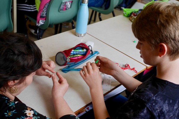 Une enseignante aide un &eacute;l&egrave;ve d'une &eacute;cole montr&eacute;alaise &agrave; confectionner une chenille-app&acirc;t qui servira &agrave; r&eacute;aliser une exp&eacute;rience de biologie en contexte r&eacute;el.