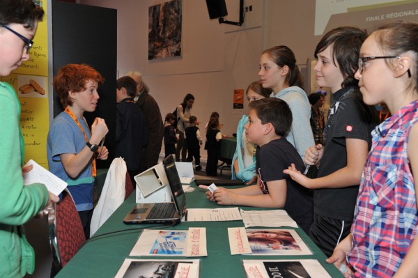 De jeunes visiteurs &eacute;coutent Elliot Christin et Jasmin Ricard pr&eacute;senter leur projet &laquo;Quel est l'effet des pubs&raquo;. Kiosque 53, &Eacute;cole des Enfants-de-la-Terre.