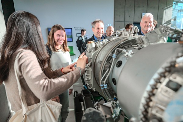 Des &eacute;tudiantes et &eacute;tudiants r&eacute;unis autour du moteur aux c&ocirc;t&eacute;s des ing&eacute;nieurs senior en gestion de projets,&nbsp;Louis-Philippe Larose et Sylvain Lamarre de Pratt & Whitney Canada.