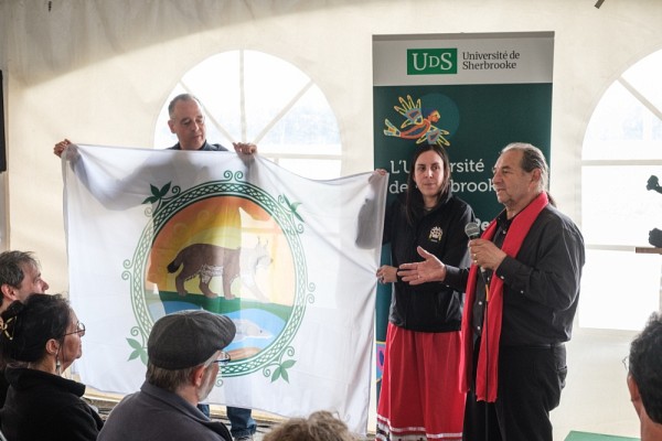 Le drapeau de la Nation W8banaki, marqu&eacute; par les symboles du lynx et de l&rsquo;esturgeon associ&eacute;s aux communaut&eacute;s de Wolinak et d&rsquo;Odanak, a &eacute;t&eacute; pr&eacute;sent&eacute; par Rick O'Bomsawin, chef de la communaut&eacute; d'Odanak, accompagn&eacute; de Suzie O&rsquo;Bomsawin, directrice g&eacute;n&eacute;rale adjointe du Conseil des Ab&eacute;nakis d&rsquo;Odanak, et de Daniel G. Nolett, directeur g&eacute;n&eacute;ral du Conseil des Ab&eacute;nakis d'Odanak.