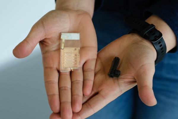 La Pre Karami tient dans ses mains des exemples de circuits microfluidiques et de micropompes.