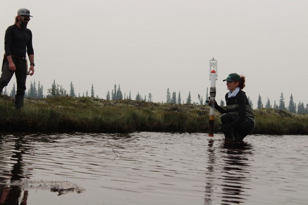 Lucile effectuant du carottage de s&eacute;diments sous l'&oelig;il de son directeur de th&egrave;se, le professeur Fr&eacute;d&eacute;ric Bouchard, et du garde-faune Sheldon Olivier, &agrave; la cam&eacute;ra.